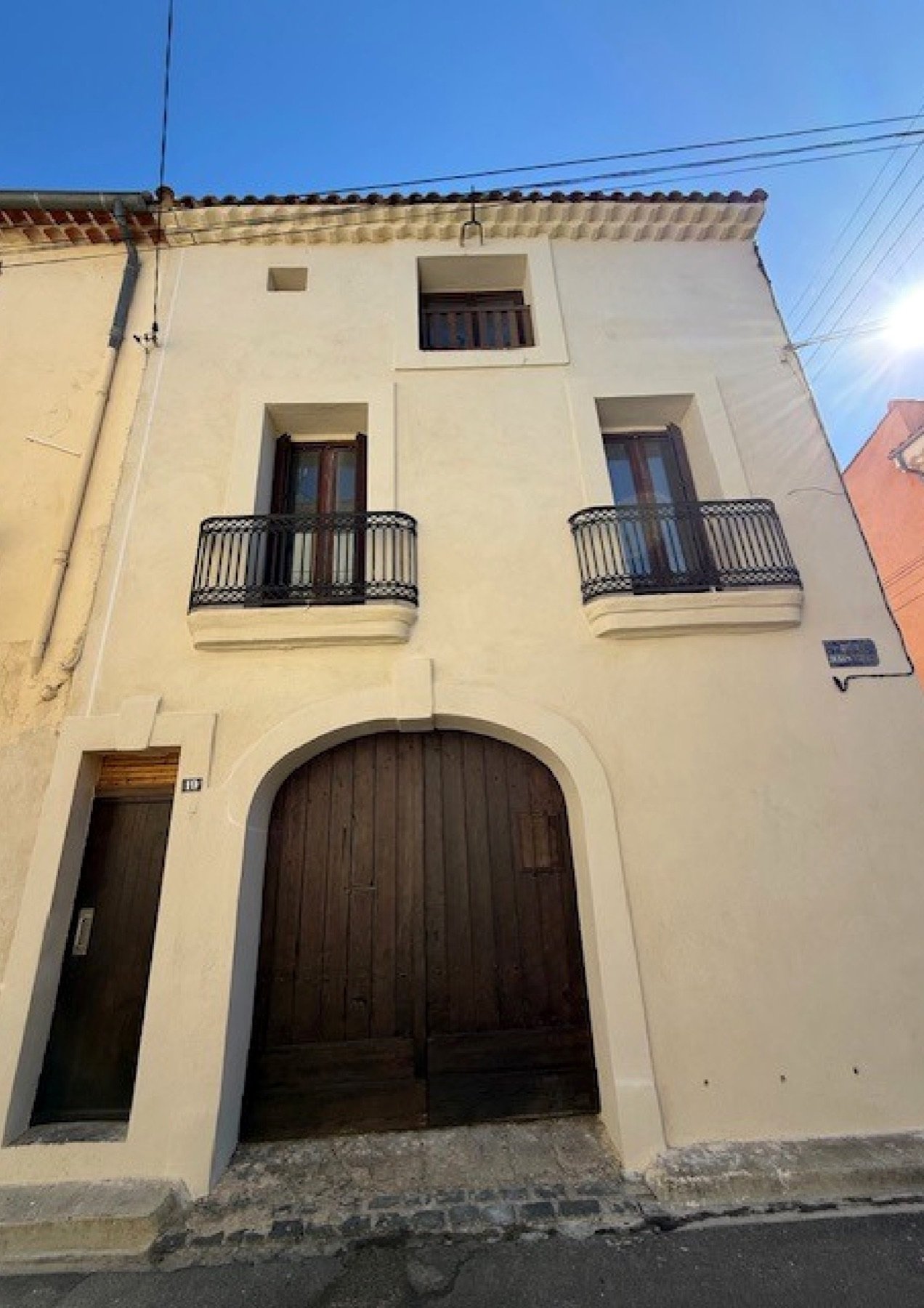 Façade rénovée du Clos des Écoles à Sérignan — balcons en fer forgé et porche d'origine