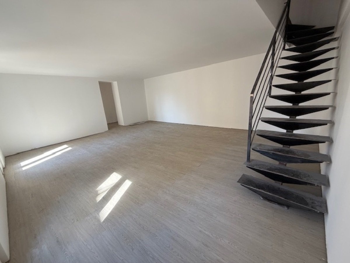 Living room of the 100 m² house: wooden floor and designer metal staircase