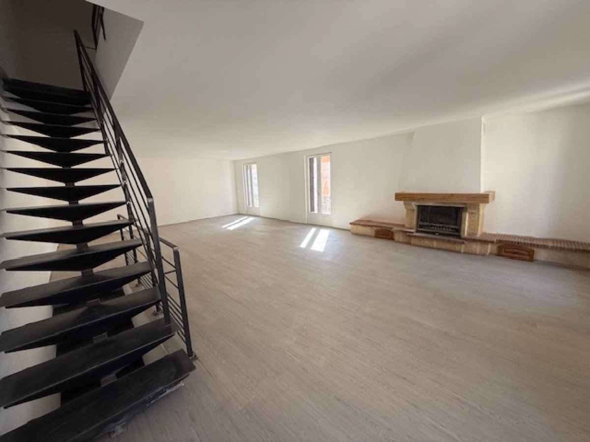 Living room of the 125 m² house: wooden floor, stone fireplace and designer staircase